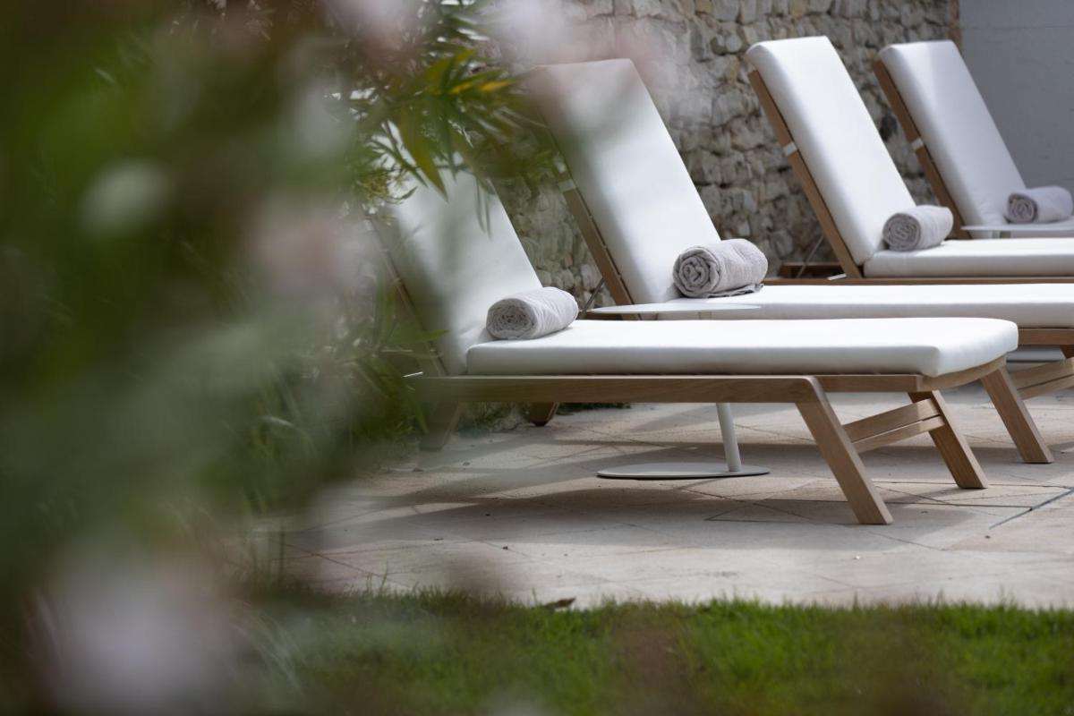 une rangée de chaises longues blanches assises sur une terrasse dans l'établissement Villa Clarisse & Spa by Olivier Claire, à Saint-Martin-de-Ré