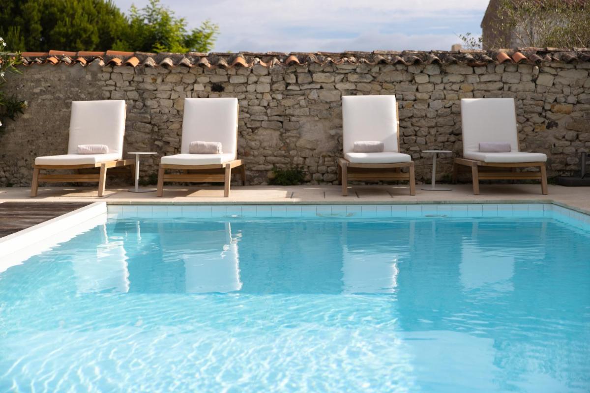 3 chaises et une piscine à côté d'un mur en pierre dans l'établissement Villa Clarisse & Spa by Olivier Claire, à Saint-Martin-de-Ré 32 autres photos