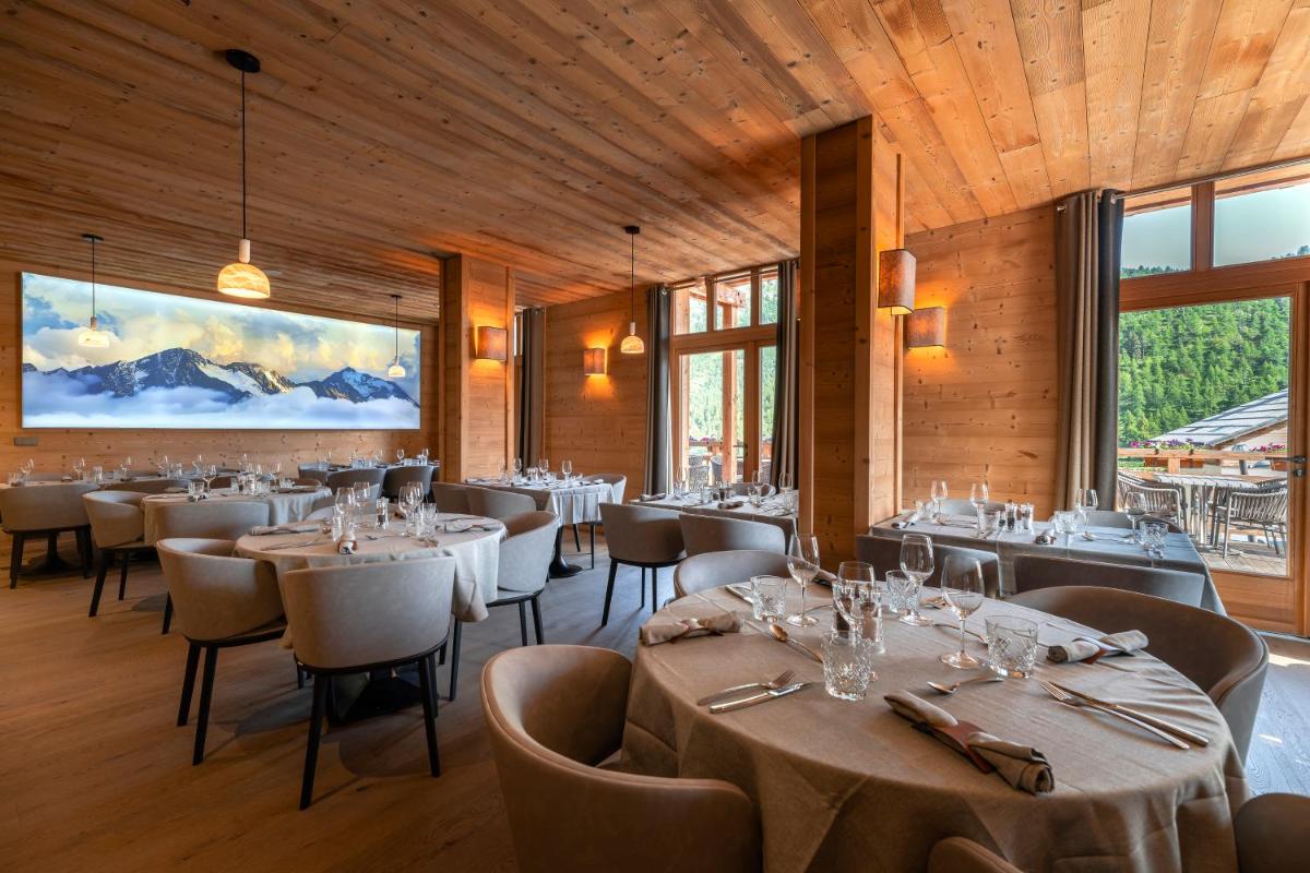 une salle à manger avec tables, chaises et fenêtres dans l'établissement Le Chalet Blanc Hôtel & Spa, à Montgenèvre