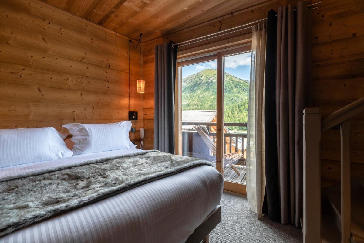une chambre avec un lit et une grande fenêtre dans l'établissement Le Chalet Blanc Hôtel & Spa, à Montgenèvre