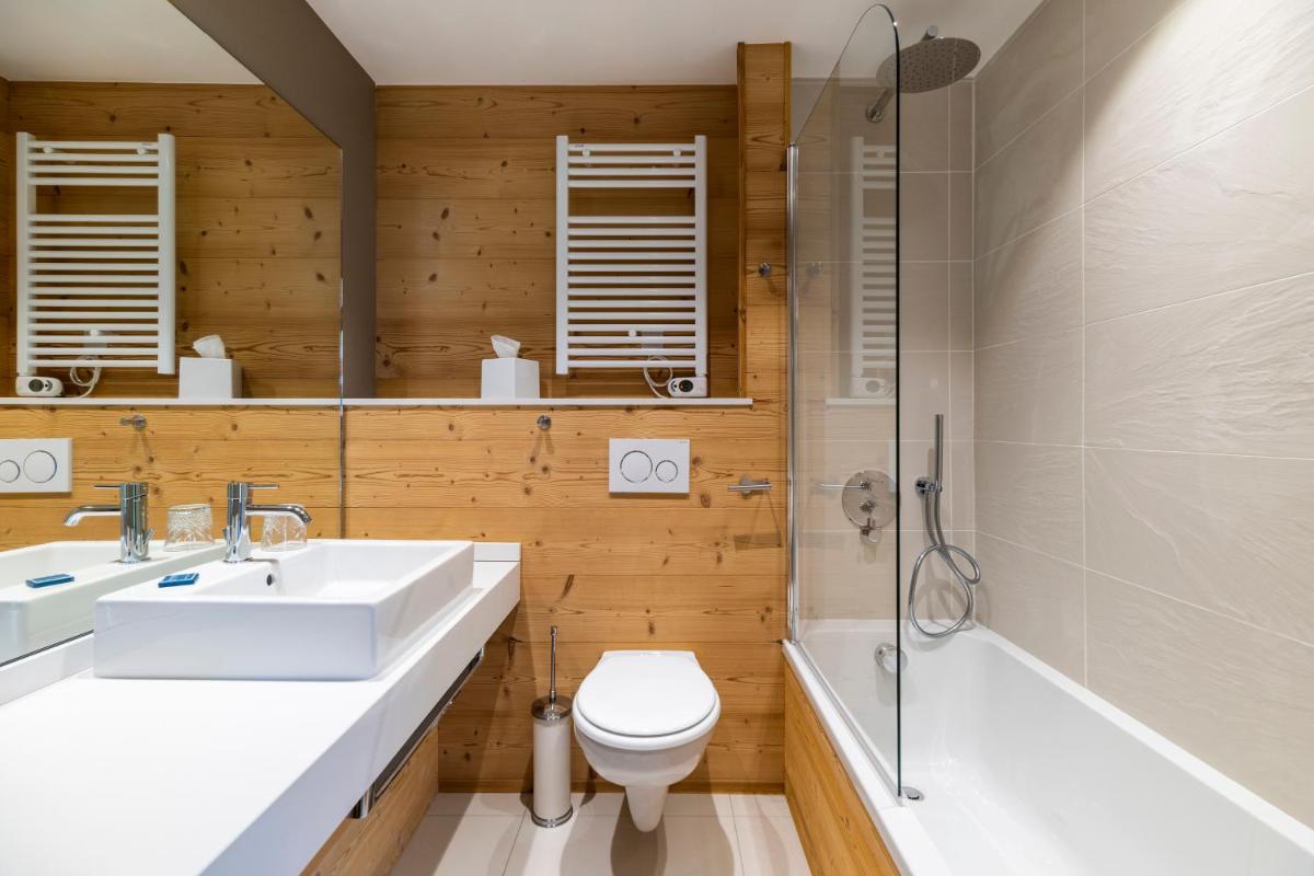 une salle de bains avec lavabo, toilettes et baignoire dans l'établissement Le Chalet Blanc Hôtel & Spa, à Montgenèvre 80 autres photos