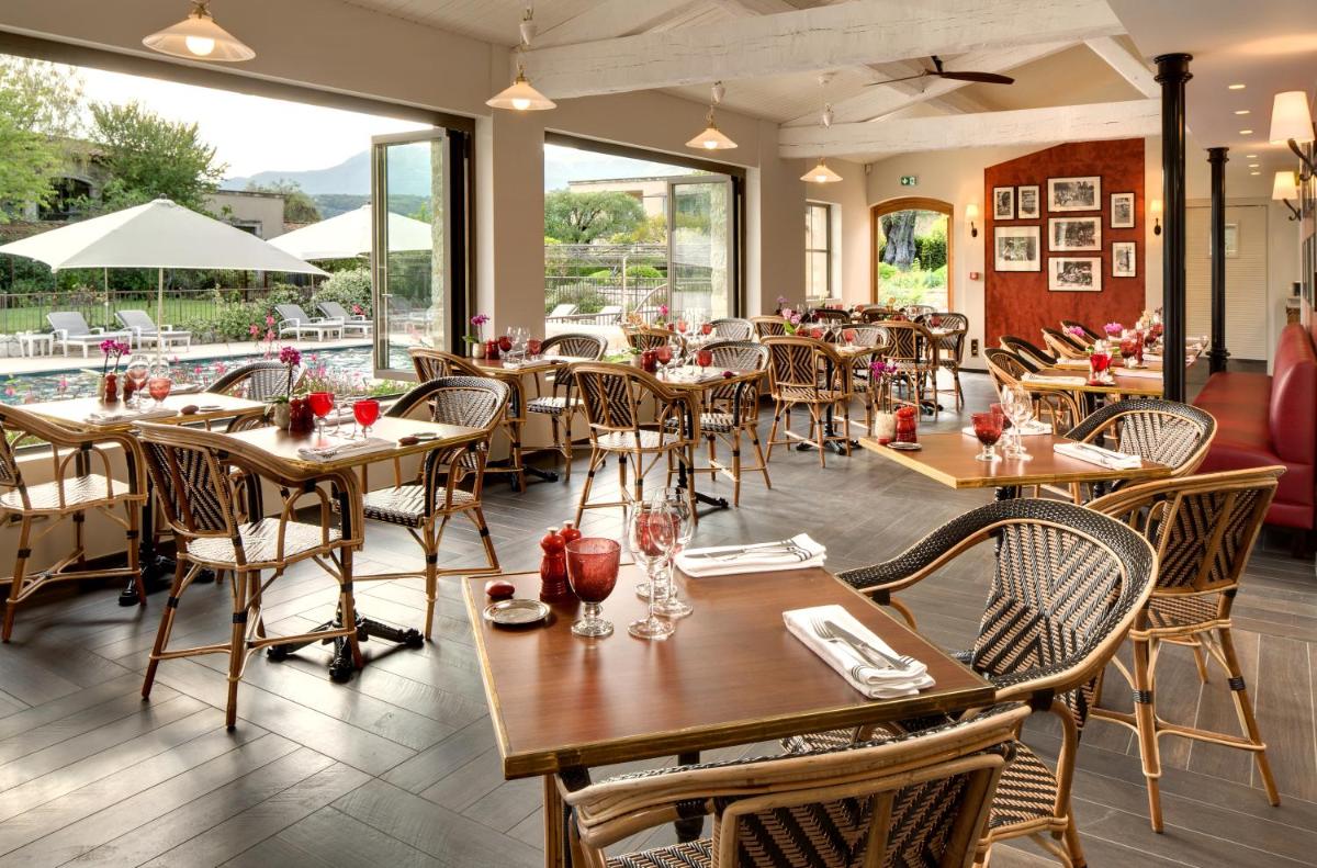 un restaurant avec des tables et des chaises en bois et des fenêtres dans l'établissement Domaine du Mas De Pierre, à Saint-Paul-de-Vence