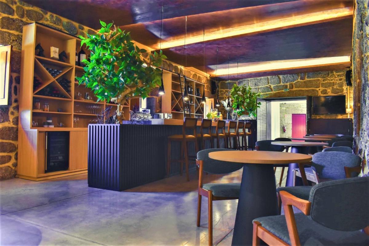 um restaurante com mesas e cadeiras e um bar em Paraíso Villas & Spa em Guimarães