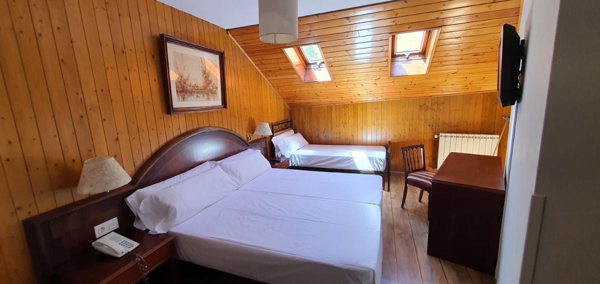 Una pequeña habitación con dos camas y un escritorio. en Balneario Caldas de Luna, en Caldas de Luna