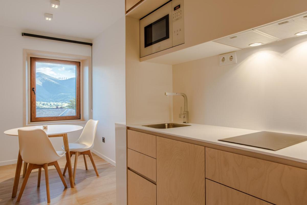 Una cocina con fregadero y una mesa con sillas. en Cerdanya Viva Ecoestades, en Prullans
