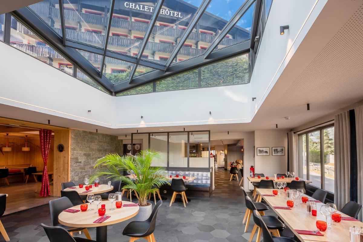 une salle à manger avec tables et chaises et une grande lucarne dans l'établissement Chalet Hôtel Le Prieuré & Spa, à Chamonix-Mont-Blanc