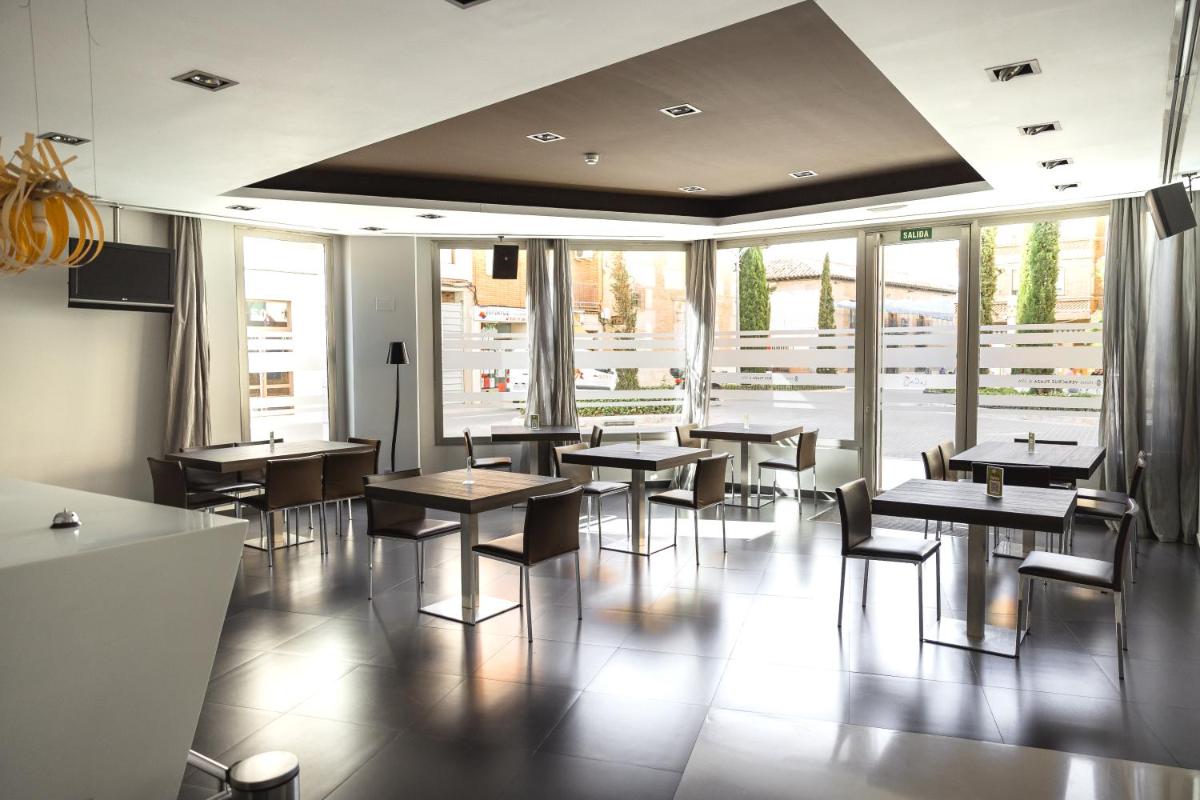 Un comedor con mesas y sillas y ventanas. en Hotel Veracruz Plaza & Spa, en Valdepeñas