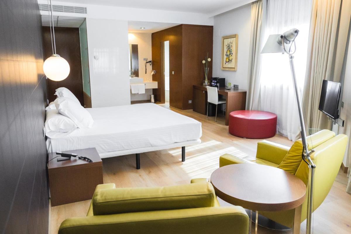 Una habitación de hotel con una cama, una mesa y sillas. en Hotel Veracruz Plaza & Spa, en Valdepeñas
