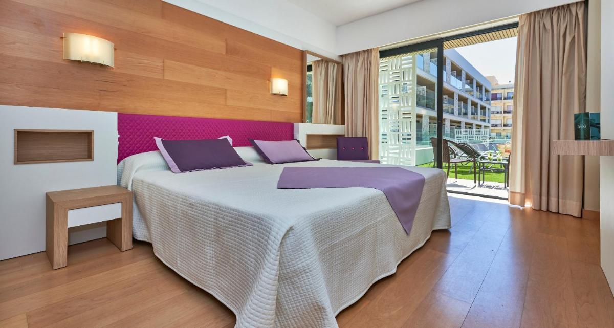 Un dormitorio con una cama grande y una ventana grande. en Hotel & Spa S'Entrador Playa, en Cala Ratjada