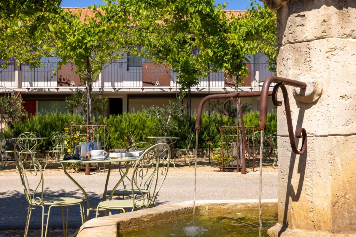 une fontaine avec des chaises dans un parc dans l'établissement Terre de Provence Hôtel & Spa, au Pontet