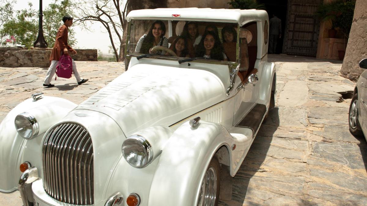 a group of people sitting in an old car at Neemrana Fort-Palace in Neemrana