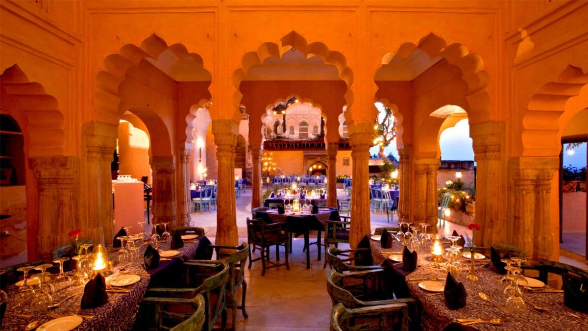 a restaurant with tables and chairs in a building at Neemrana Fort-Palace in Neemrana