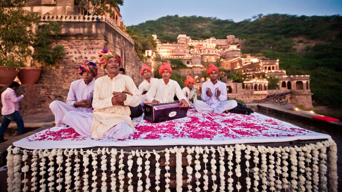 a group of people sitting on a blanket of flowers at Neemrana Fort-Palace in Neemrana