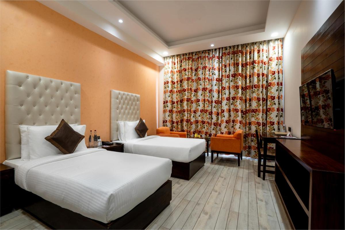 a hotel room with two beds and a desk at The Orchid Shimla in Shimla