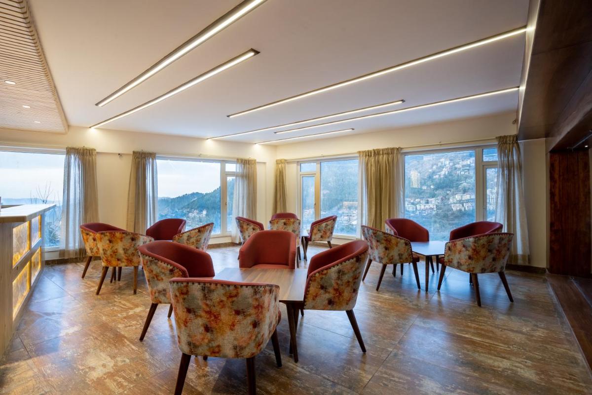 a dining room with a table and chairs and windows at The Orchid Shimla in Shimla