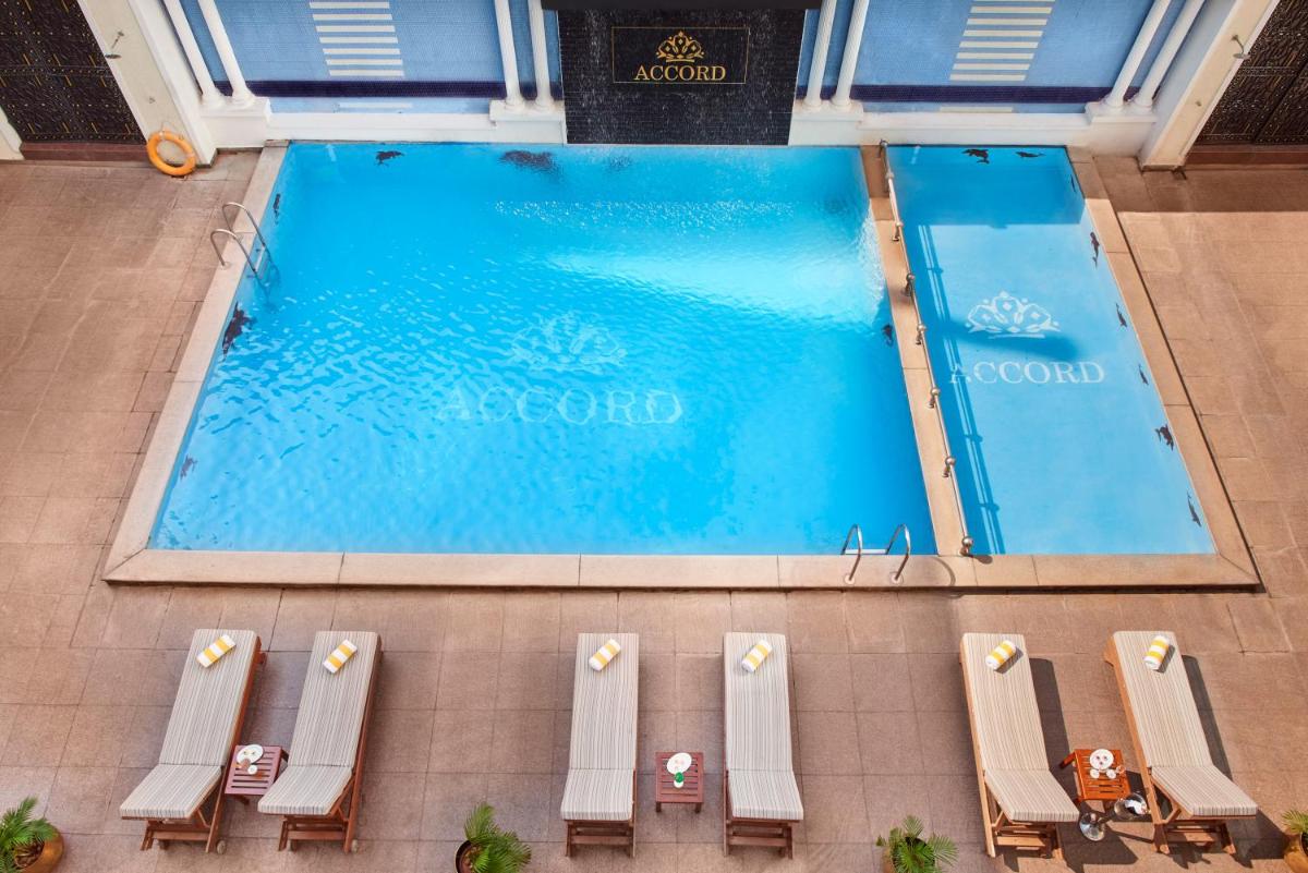 an overhead view of a large swimming pool with chaises and chairs at Accord Puducherry in Puducherry