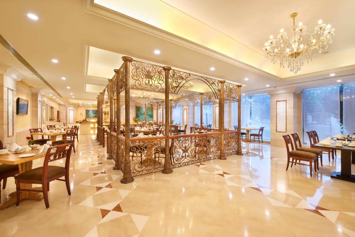 a dining room with tables and chairs and a chandelier at Accord Puducherry in Puducherry