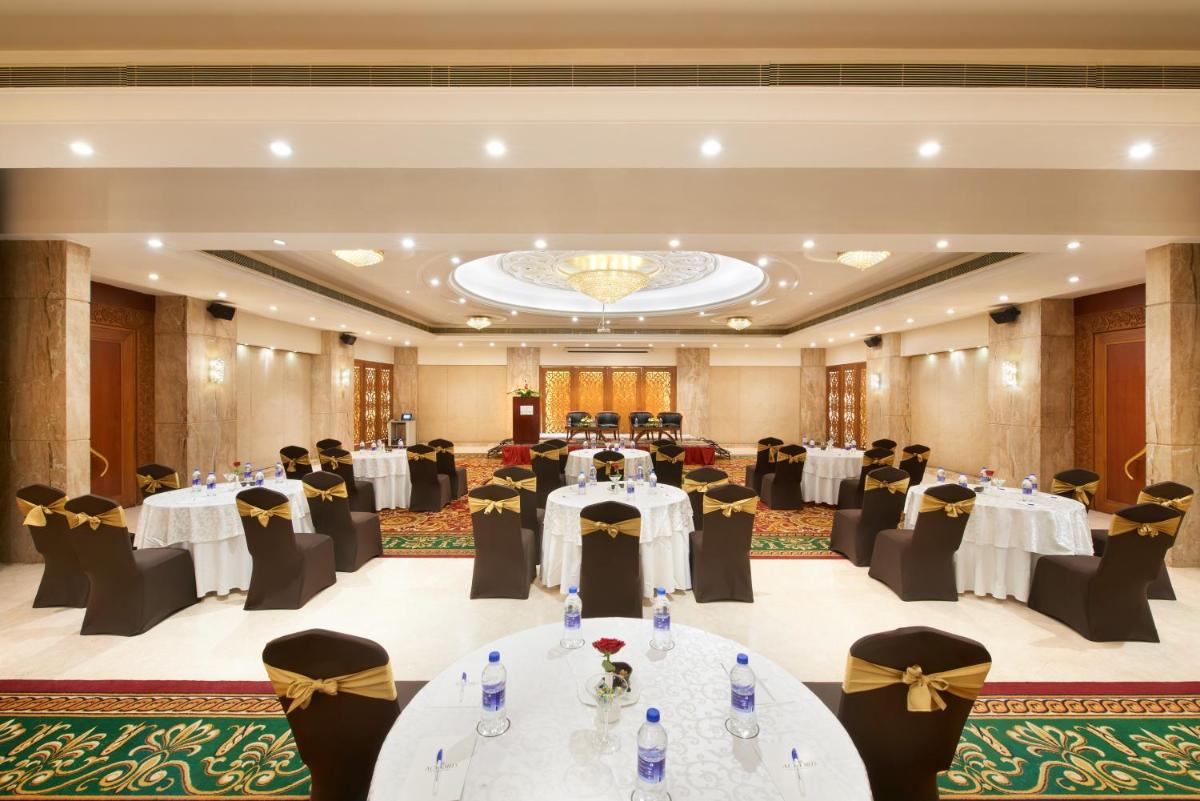 a banquet hall with white tables and black chairs at Accord Puducherry in Puducherry