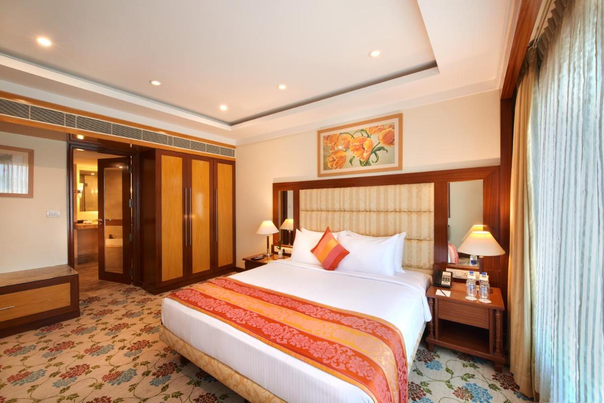 a hotel room with a large bed and a television at Accord Puducherry in Puducherry
