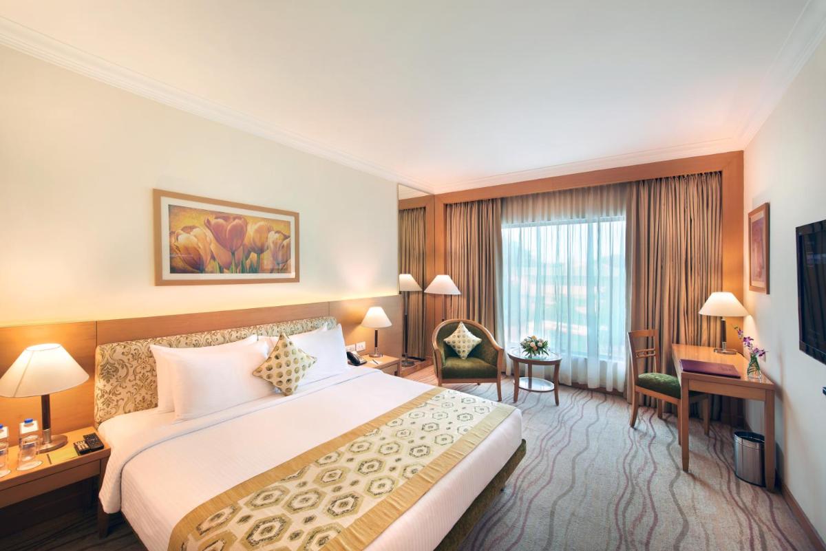 a hotel room with a bed and a desk at Accord Puducherry in Puducherry