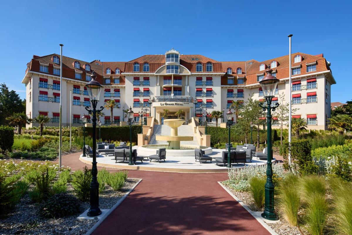 un grand bâtiment avec une fontaine devant lui dans l'établissement Le Grand Hôtel Le Touquet-Paris-Plage, à Le Touquet-Paris-Plage
