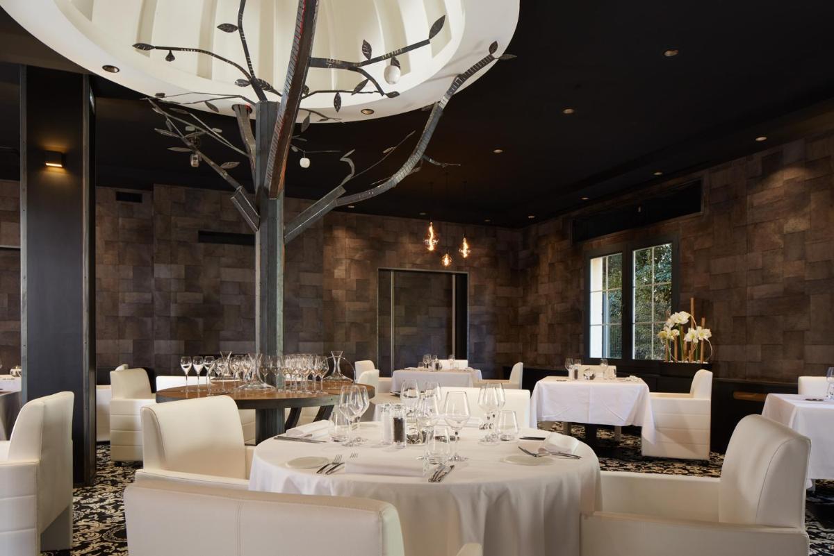 un restaurant avec des tables et des chaises blanches et un grand lustre dans l'établissement Le Grand Hôtel Le Touquet-Paris-Plage, à Le Touquet-Paris-Plage