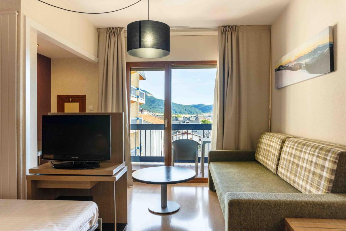 Una sala de estar con un sofá y un televisor. en Oroel Hotel & SPA, en Jaca