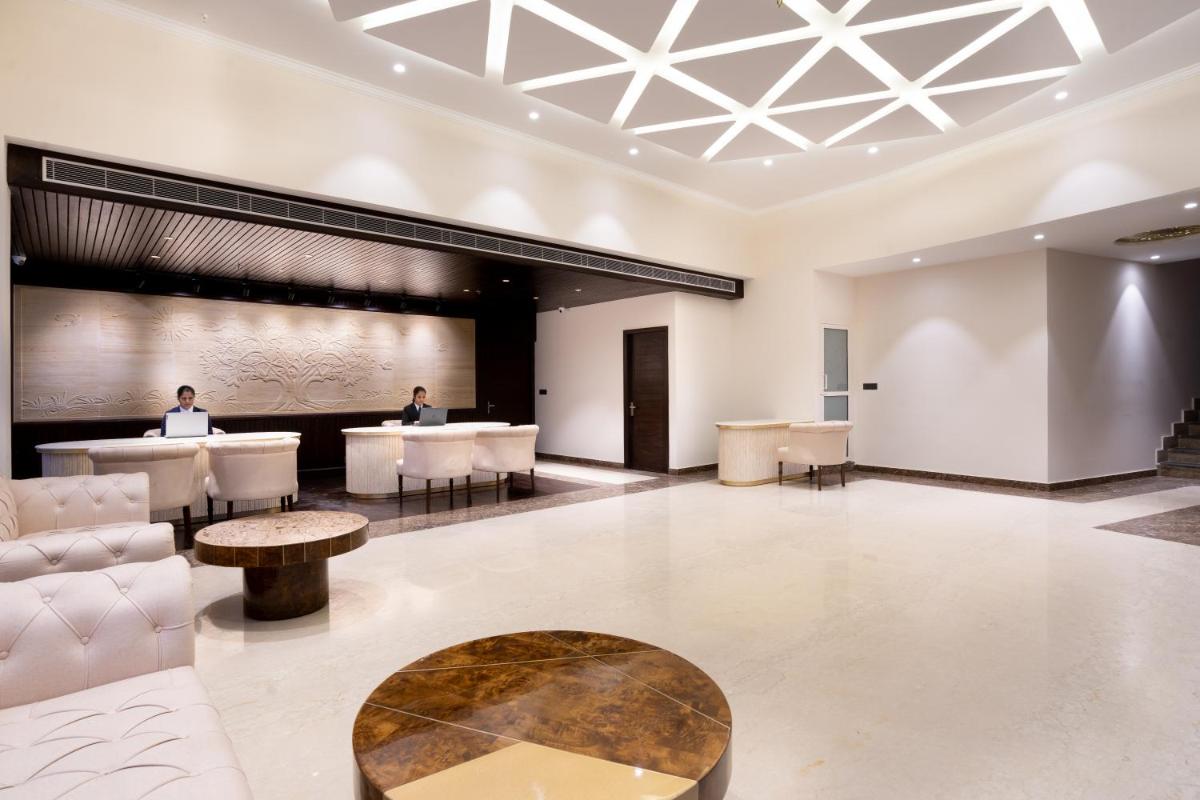a lobby with white furniture and a table at The Orchid Shimla in Shimla