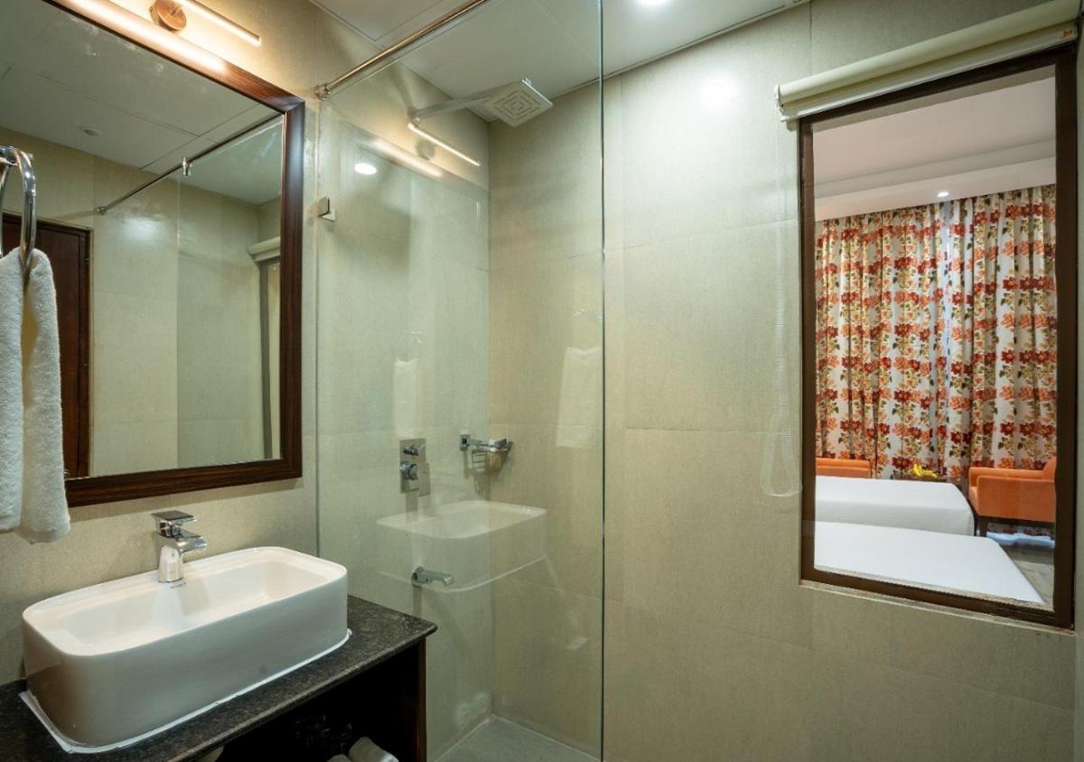 a bathroom with a sink and a shower with a mirror at The Orchid Shimla in Shimla