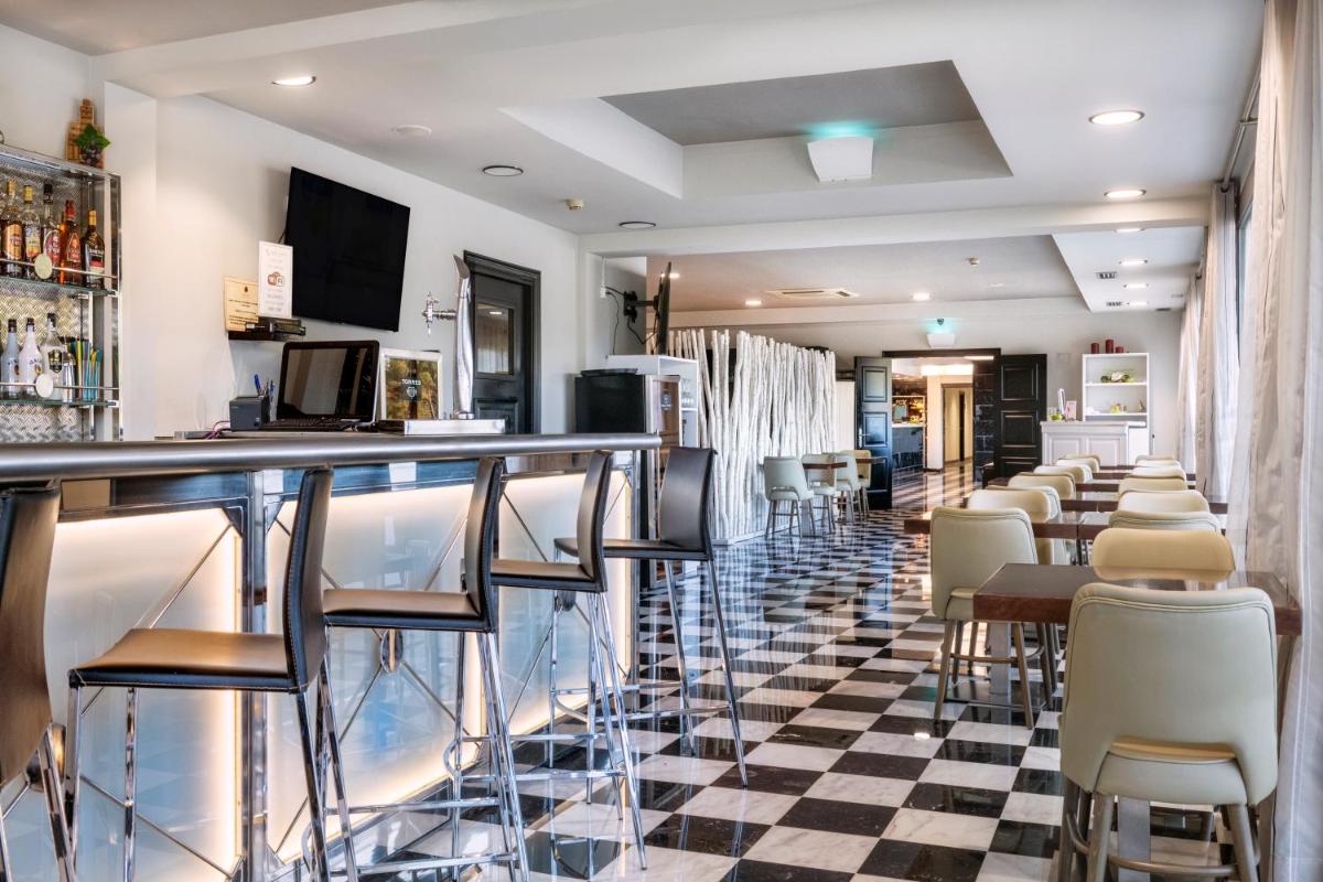 un bar en un restaurante con suelo a cuadros en Salles Hotel Aeroport de Girona, en Riudellots de la Selva