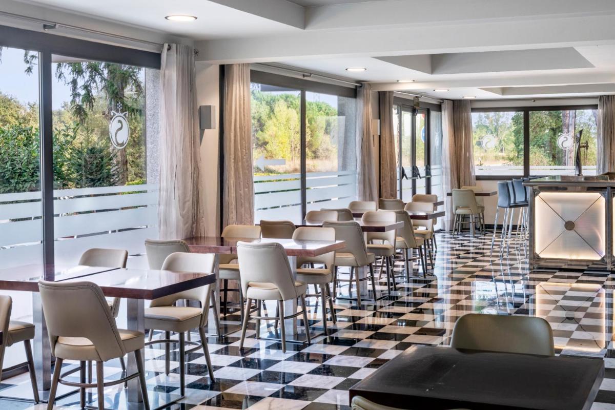 Un restaurante con mesas y sillas sobre un suelo a cuadros. en Salles Hotel Aeroport de Girona, en Riudellots de la Selva