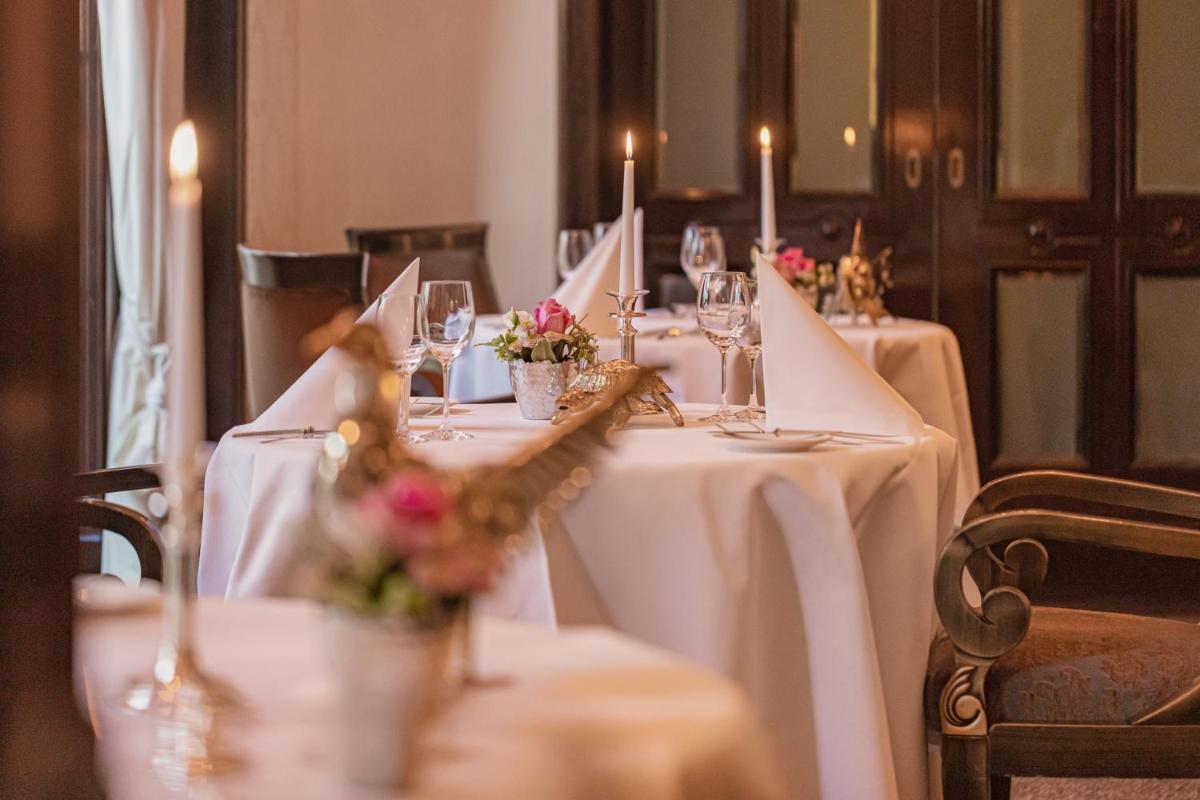 eine Gruppe von Tischen mit weißen Tischdecken und Kerzen in der Unterkunft Wald & Schlosshotel Friedrichsruhe in Friedrichsruhe + 105 Fotos