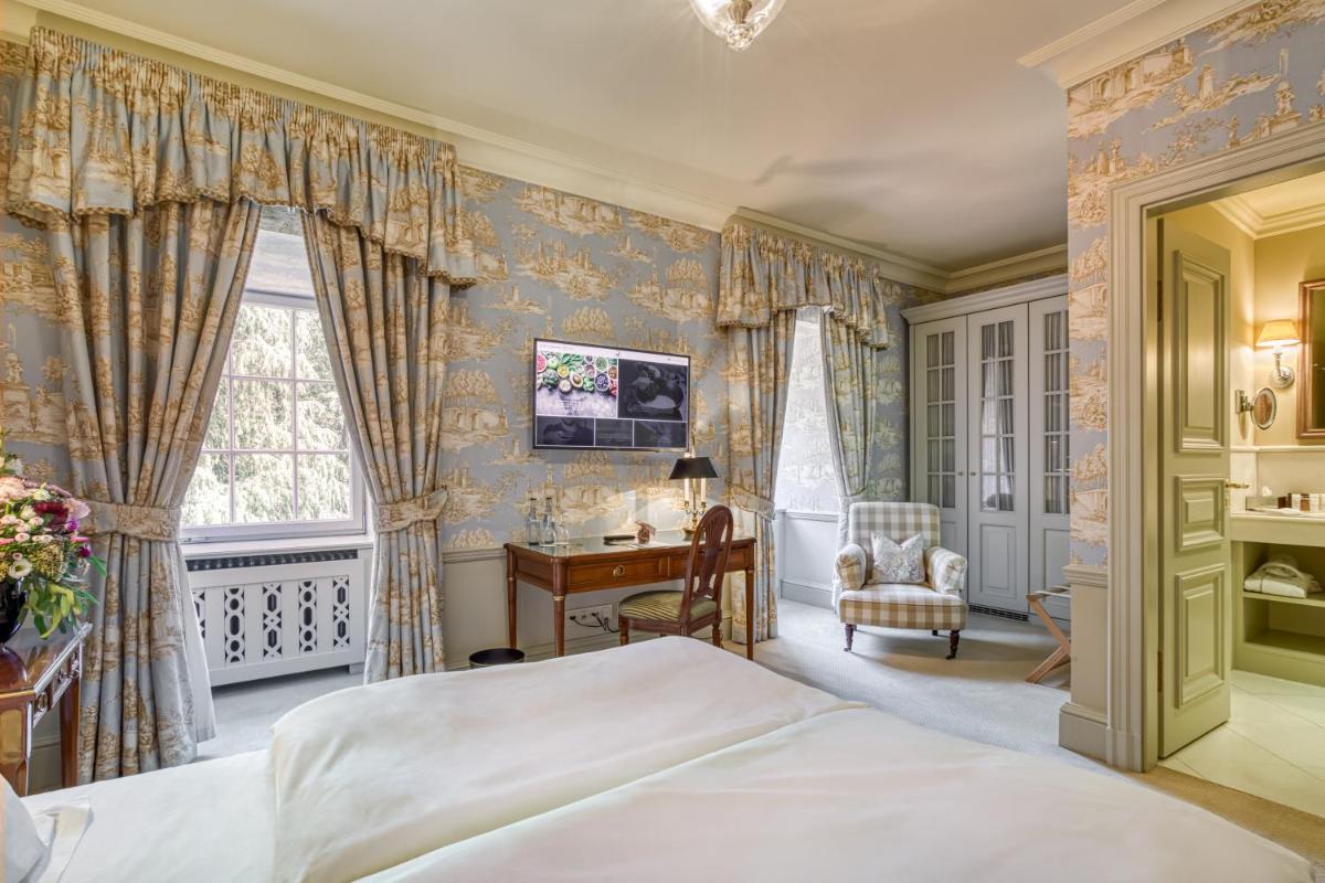 ein Schlafzimmer mit Bett, Schreibtisch und Fenster in der Unterkunft Wald & Schlosshotel Friedrichsruhe in Friedrichsruhe