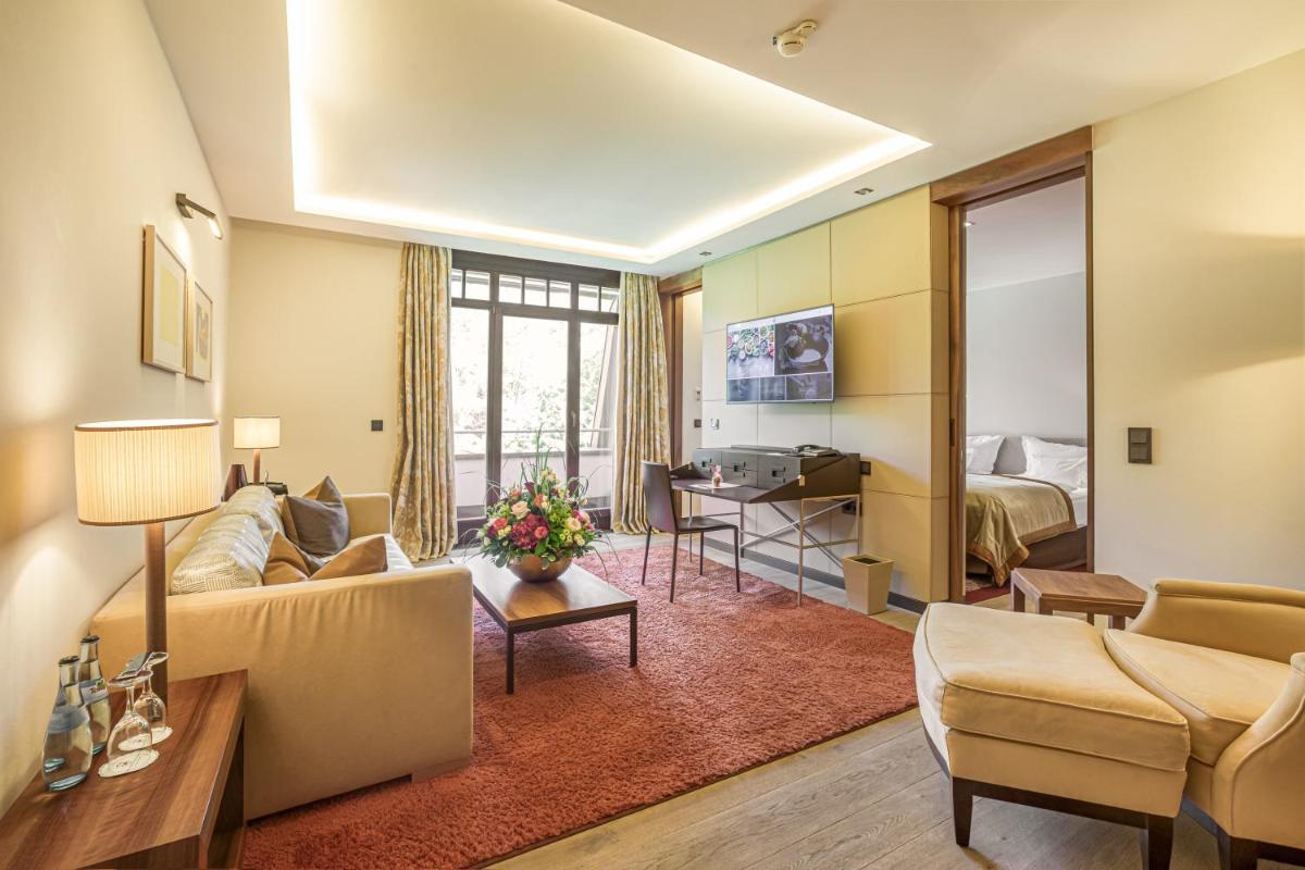 ein Wohnzimmer mit Sofa und Schreibtisch in der Unterkunft Wald & Schlosshotel Friedrichsruhe in Friedrichsruhe