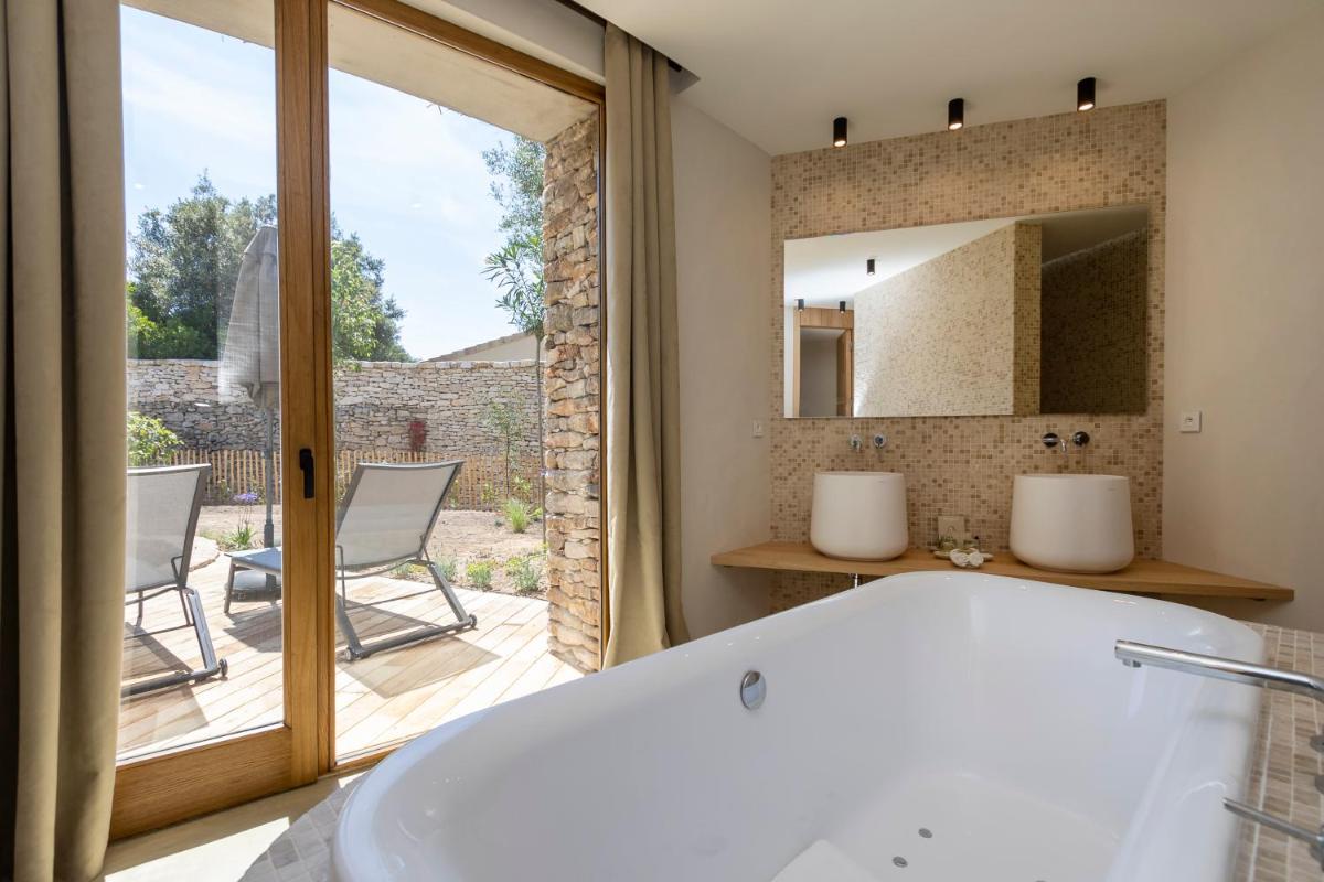 La salle de bains est pourvue d'une baignoire. dans l'établissement A SPERANZA Suites avec piscine privative chauffée, à Bonifacio