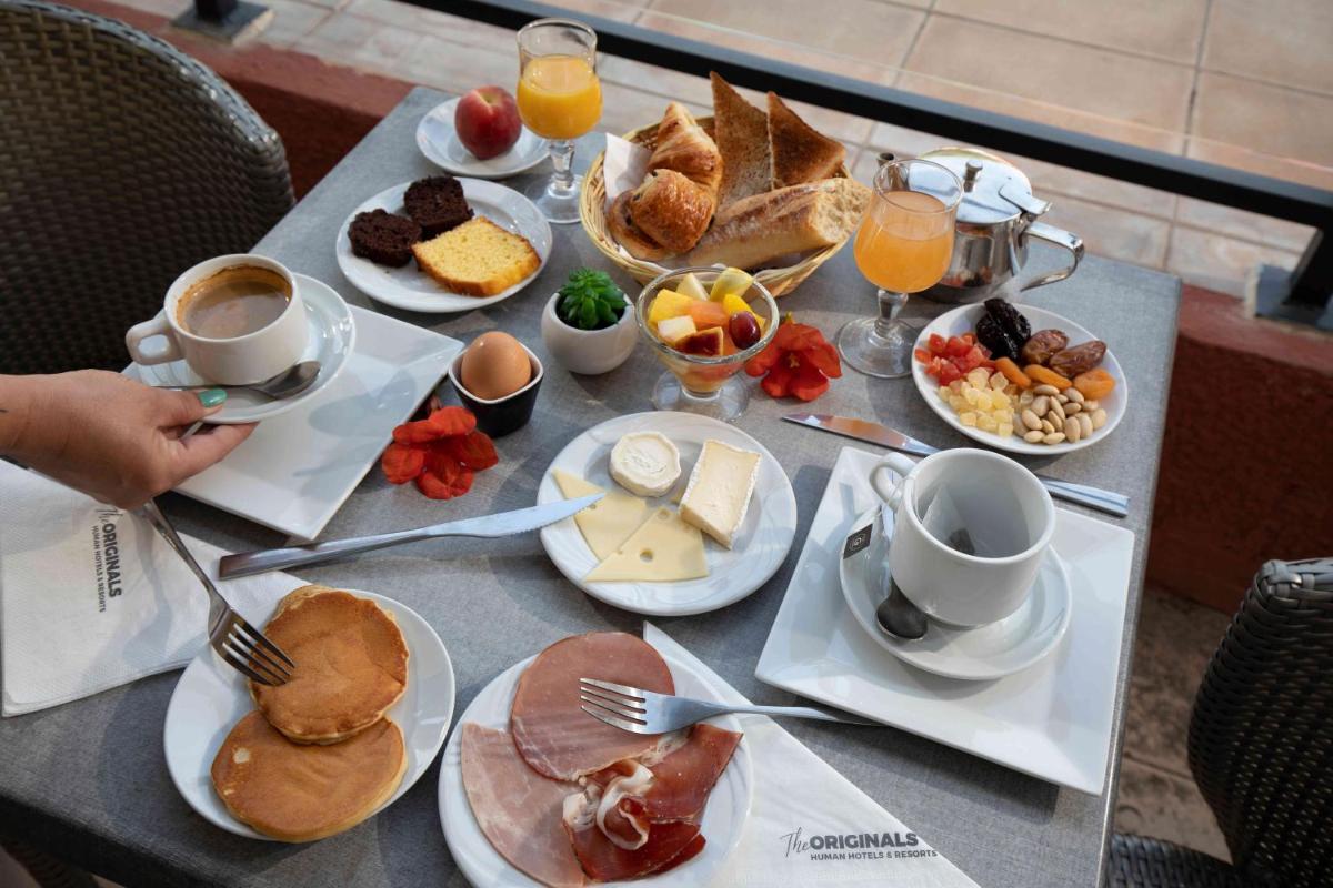une table avec des aliments et des boissons pour le petit-déjeuner dessus dans l'établissement Relax'Otel & Spa, Le Barcarès, au Barcarès