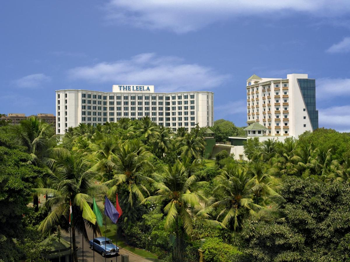 a hotel with palm trees in front of a building at The Leela Mumbai in Mumbai a hotel with palm trees in front of a building at The Leela Mumbai in Mumbai