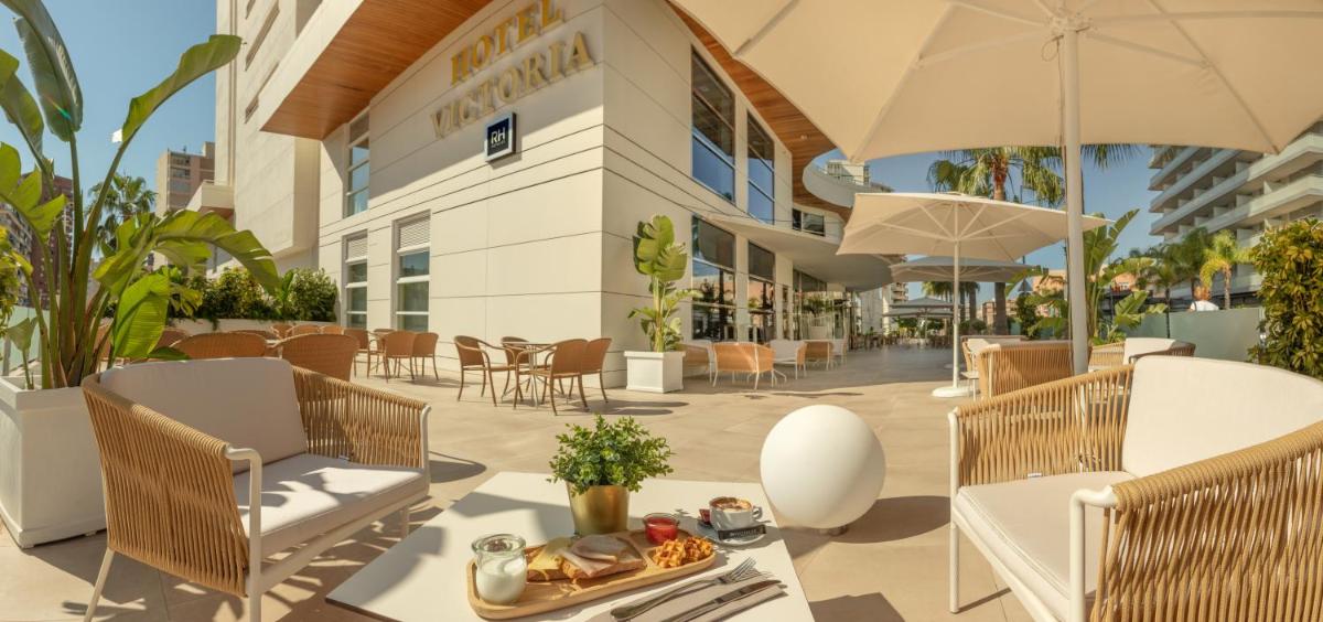 un patio al aire libre con mesa, sillas y sombrilla en Hotel RH Victoria & Spa 4 Sup, en Benidorm