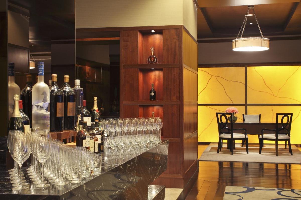 a bar with wine glasses and bottles of wine at The Leela Ambience Gurugram Hotel & Residences - The Luxury Urban Sanctuary in Gurgaon