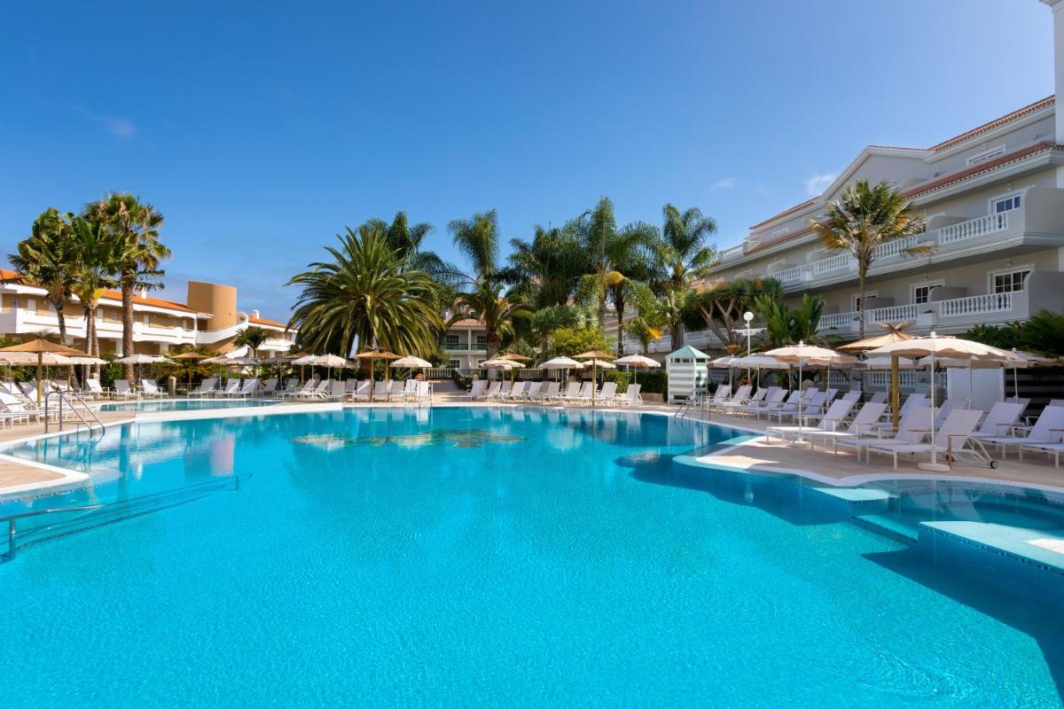 una gran piscina con sillas y sombrillas en Hotel RIU Garoé, en Puerto de la Cruz