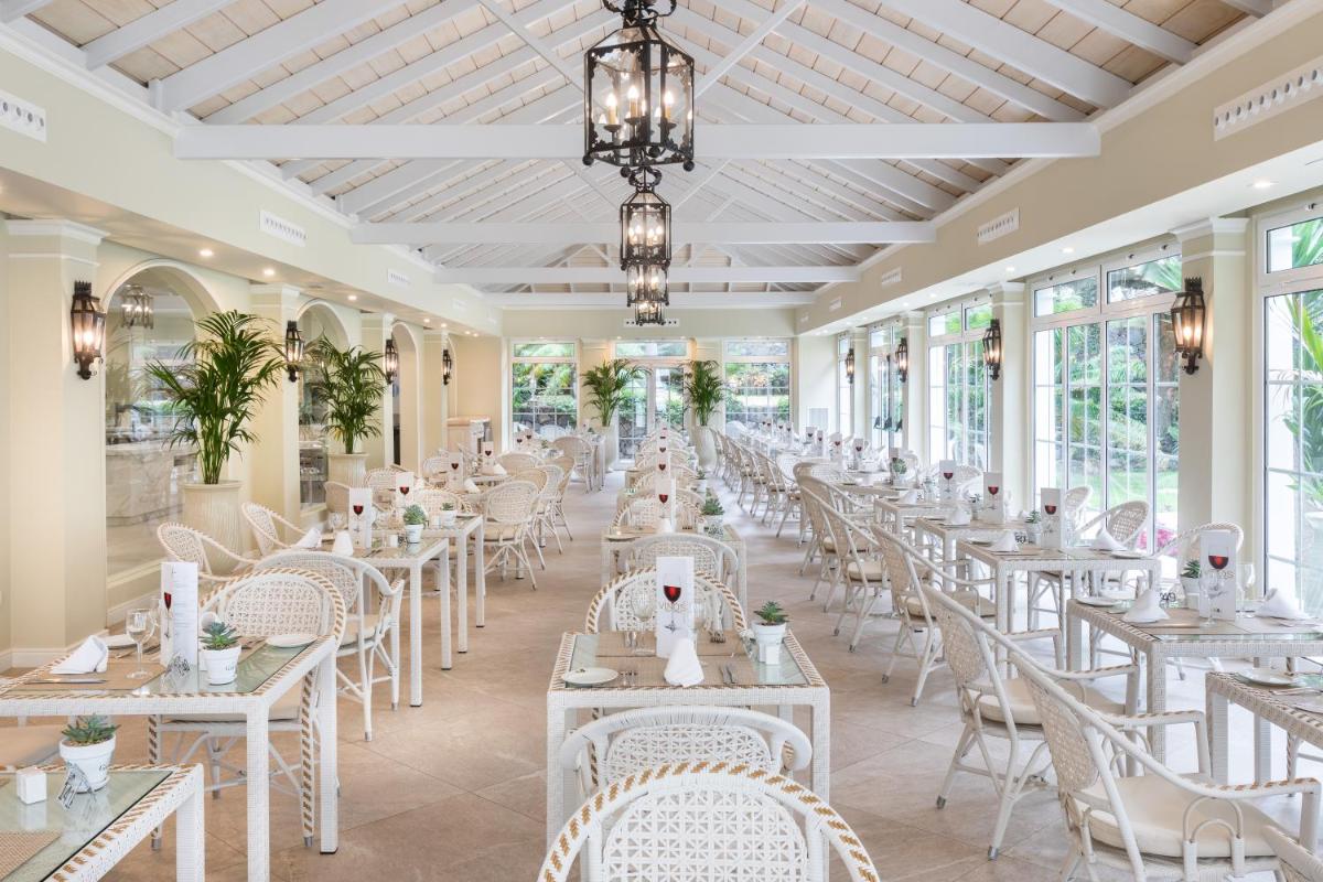 Una fila de mesas y sillas en una habitación con ventanas. en Hotel RIU Garoé, en Puerto de la Cruz