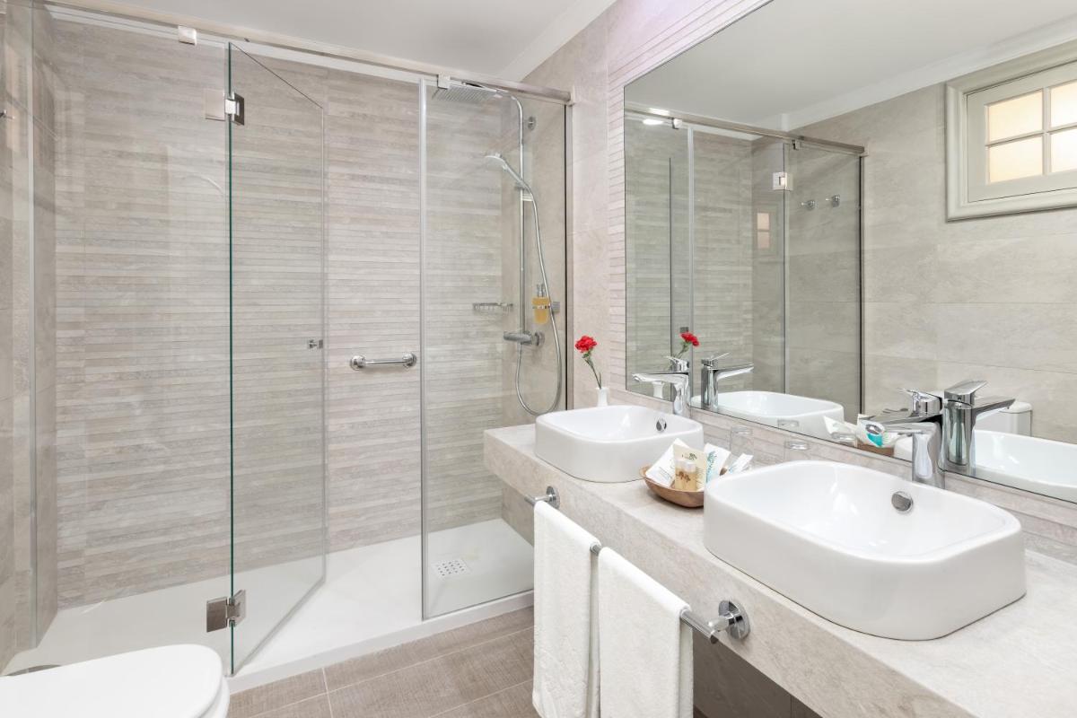 Un baño con dos lavabos y una ducha de cristal. en Hotel RIU Garoé, en Puerto de la Cruz