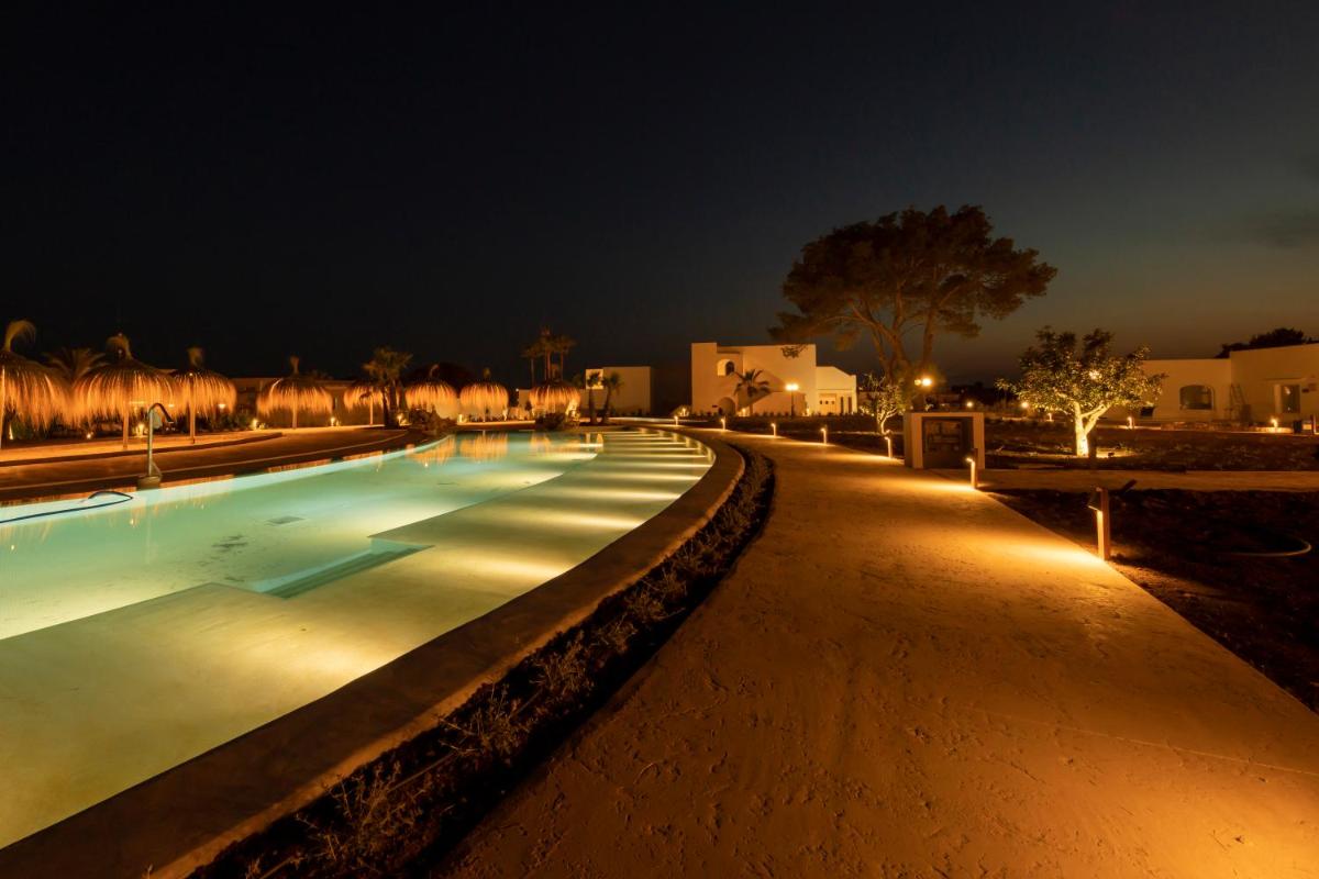 Una piscina vacía por la noche con luces. en Eques Petit Resort, en Cala d´Or