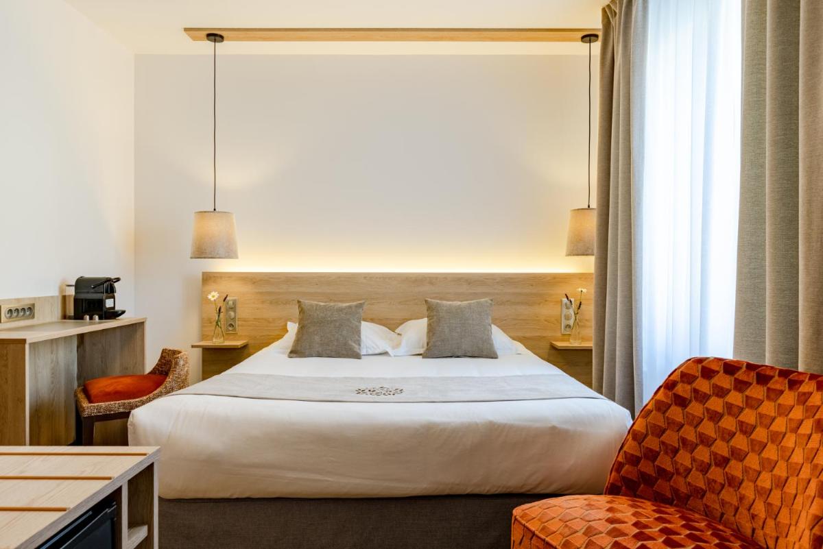 une chambre d'hôtel avec un grand lit et deux chaises dans l'établissement Hôtel SPA du Lac de Madine - Maison DRAPIER, à Heudicourt-sous-les-Côtes