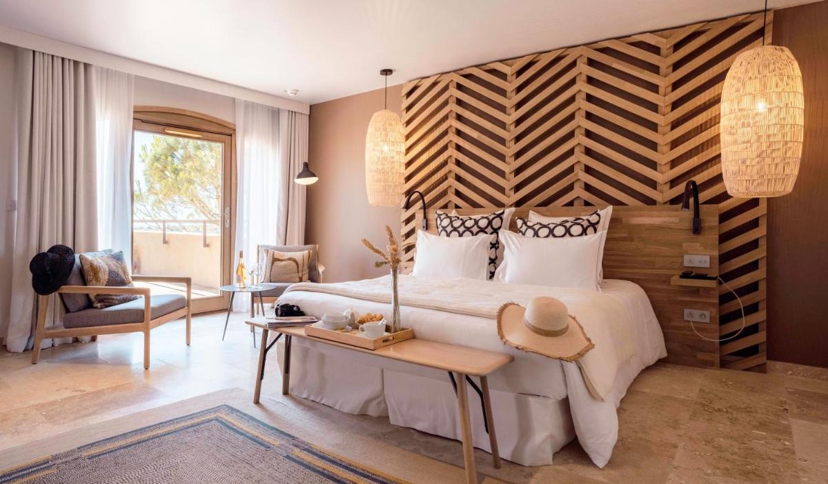 une chambre avec un grand lit avec une tête de lit en bois dans l'établissement Château L'Hospitalet Wine Resort Beach & Spa, à Narbonne