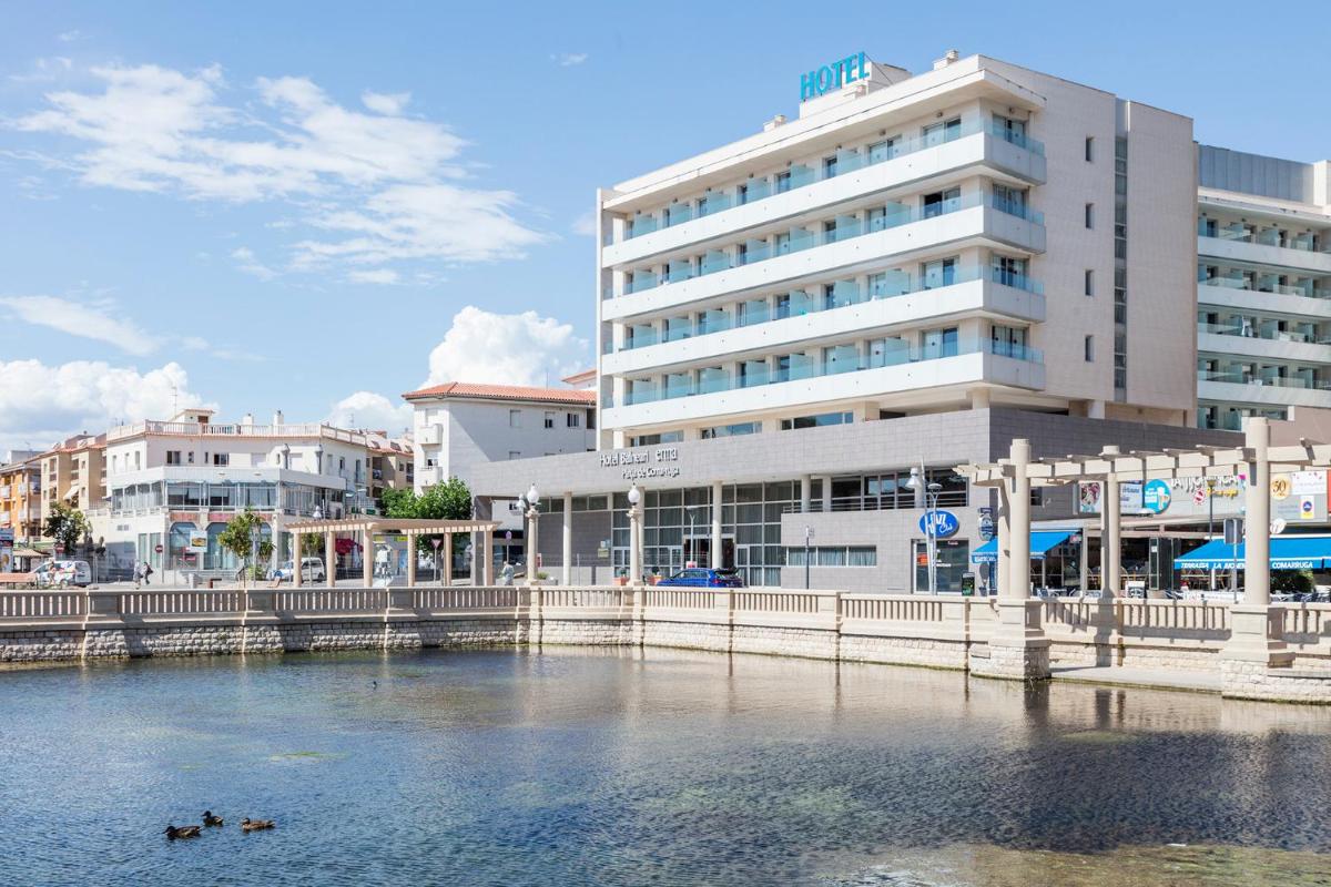 dos patos en el agua frente a un edificio en Hotel Balneario Playa de Comarruga, en Comarruga
