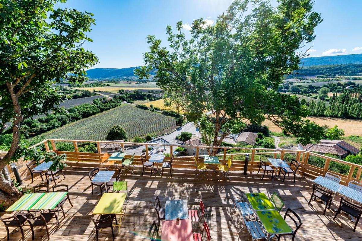 un patio extérieur avec tables et chaises et une vue sur la campagne dans l'établissement Le Nesk Ventoux - Hotel, à Sault