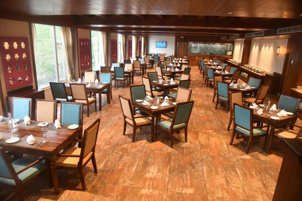 a dining room filled with tables and chairs at The Orchid Shimla in Shimla