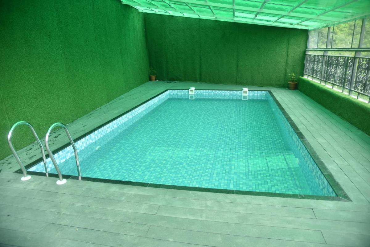 an empty swimming pool in a green room with at The Orchid Shimla in Shimla