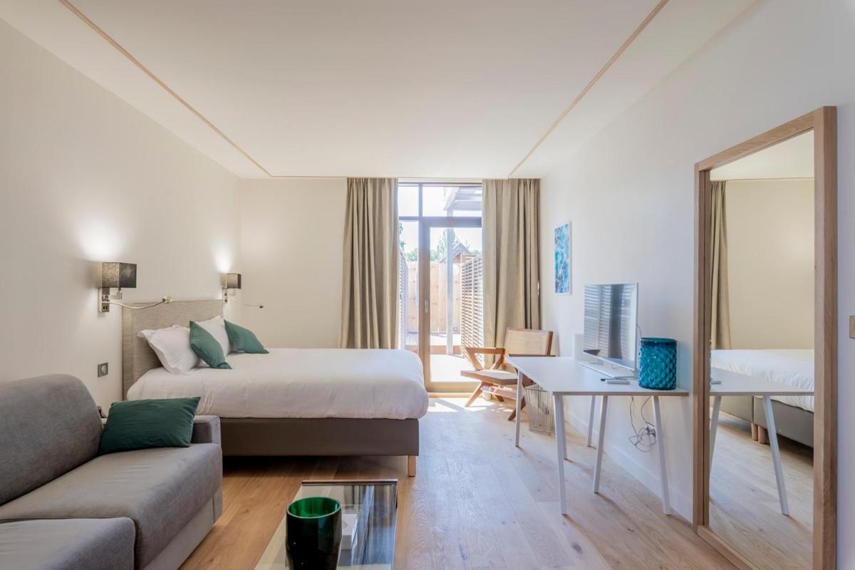 une chambre d'hôtel avec un lit et un canapé dans l'établissement Résidence Les Suites du Port - by Le Saint Ferdinand, à Arcachon